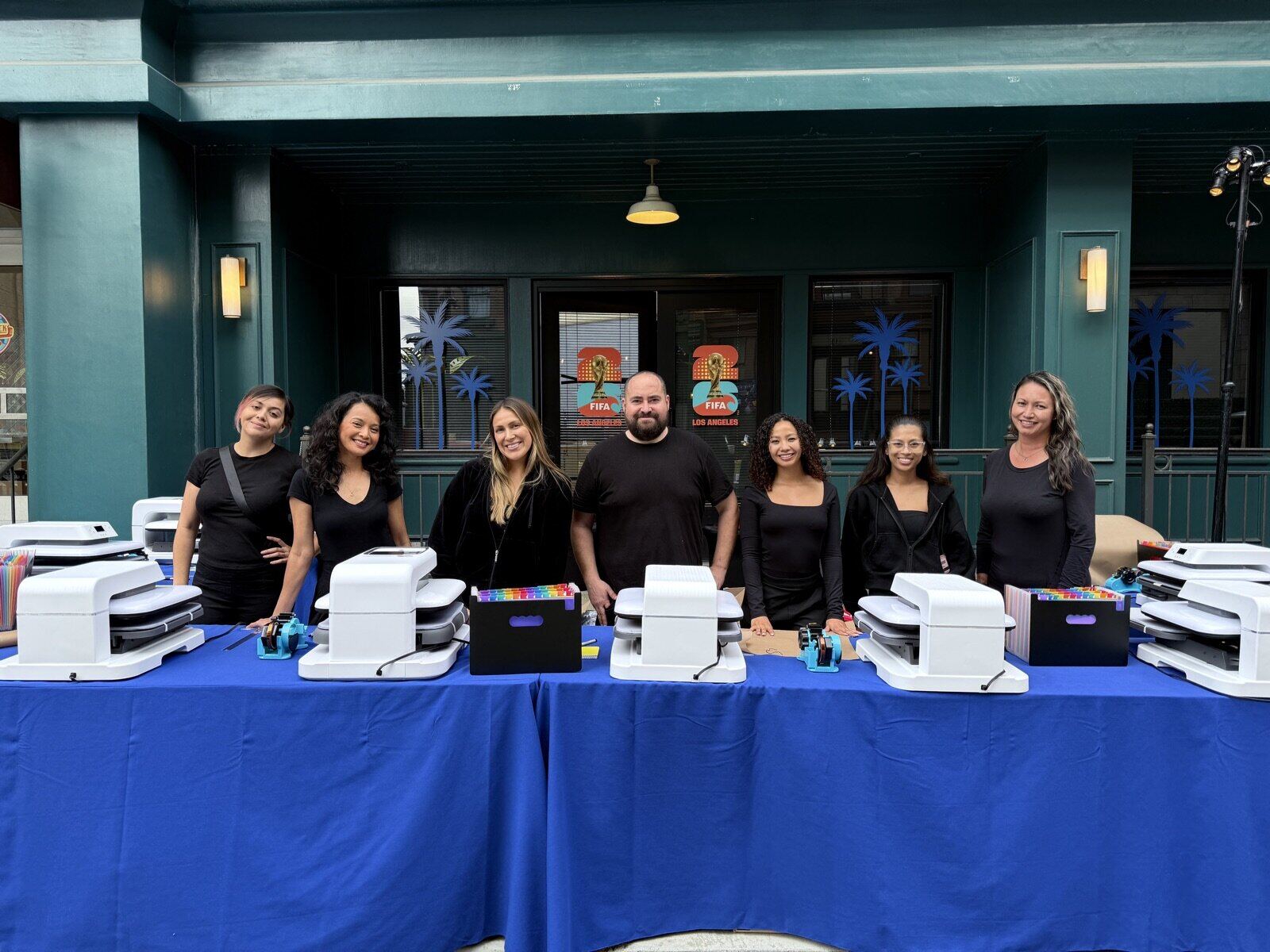 Outdoor printing station with heat presses and crew at a street festival