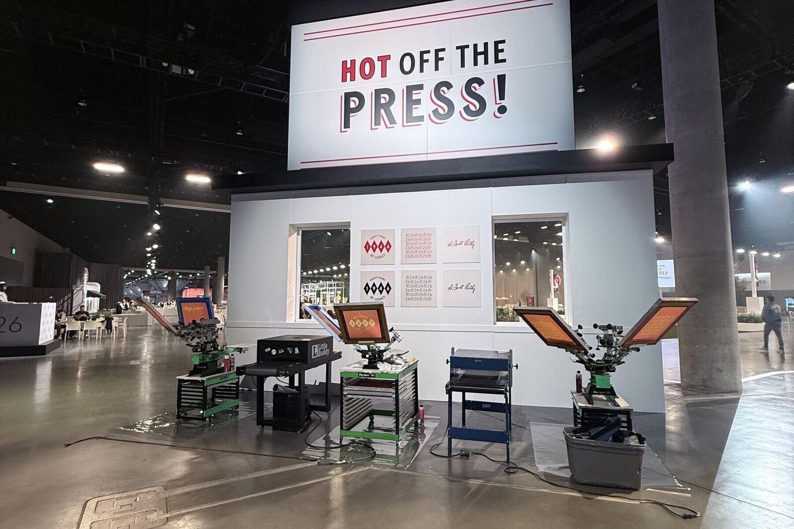 Hot Off The Press booth with three screen-printing presses ready to run at a convention center